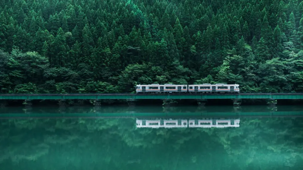 翠色山林间行驶的列车与平静水面倒影 高清4K壁纸 3840×2160